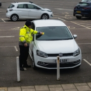 man in yellow jacket standing beside white car