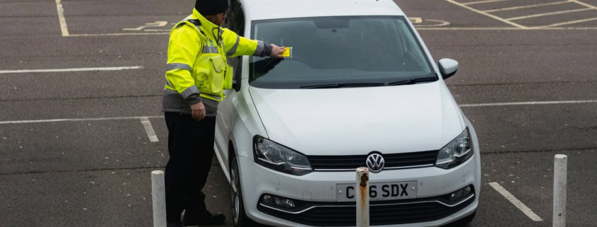 man in yellow jacket standing beside white car